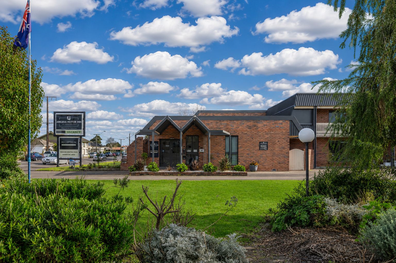 A brick building with a reception area, a sign indicating vacancy, and a flagpole with a flag.
