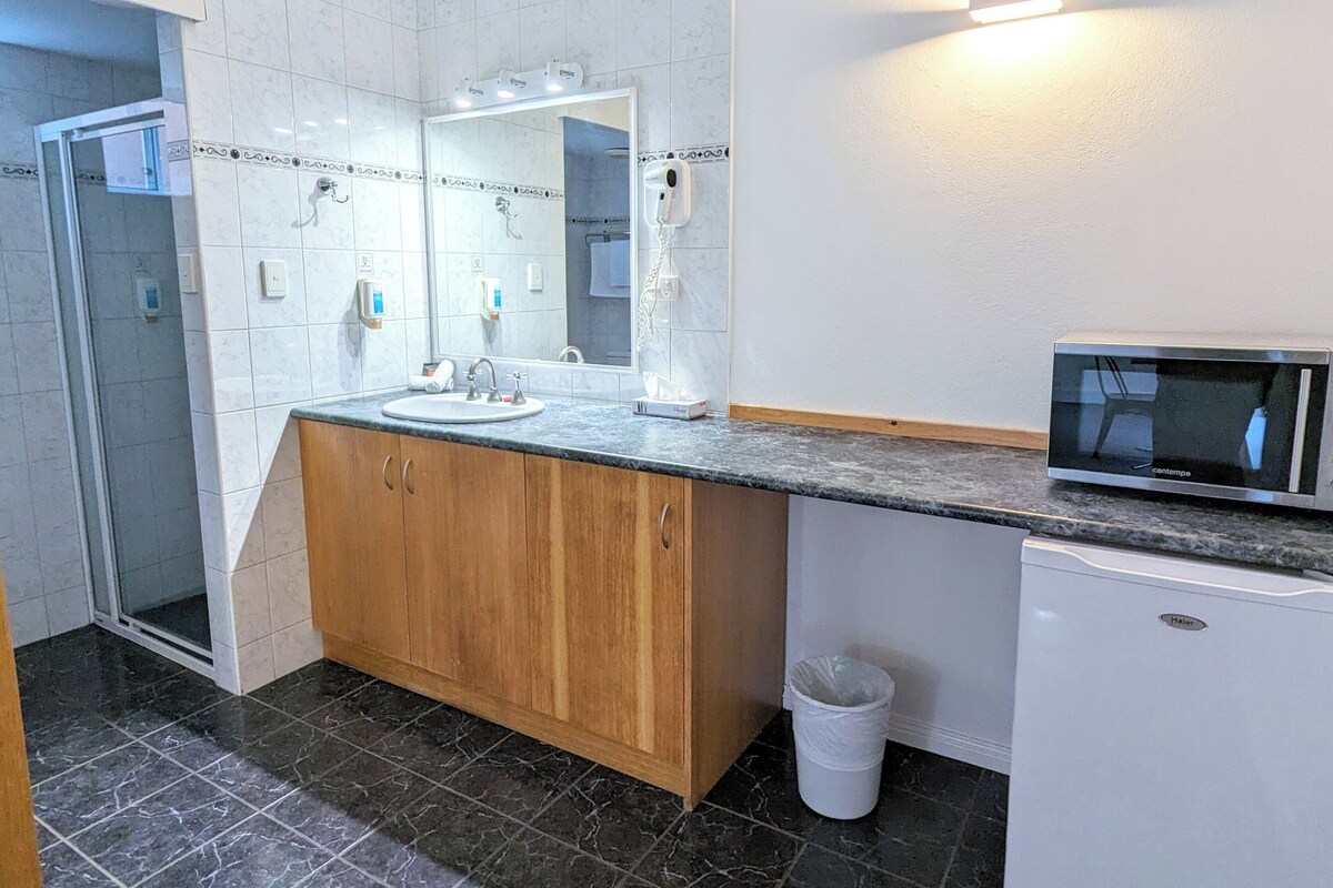 Une salle de bain équipée d’un lavabo, d’un miroir, d’un meuble-lavabo et d’un four à micro-ondes.