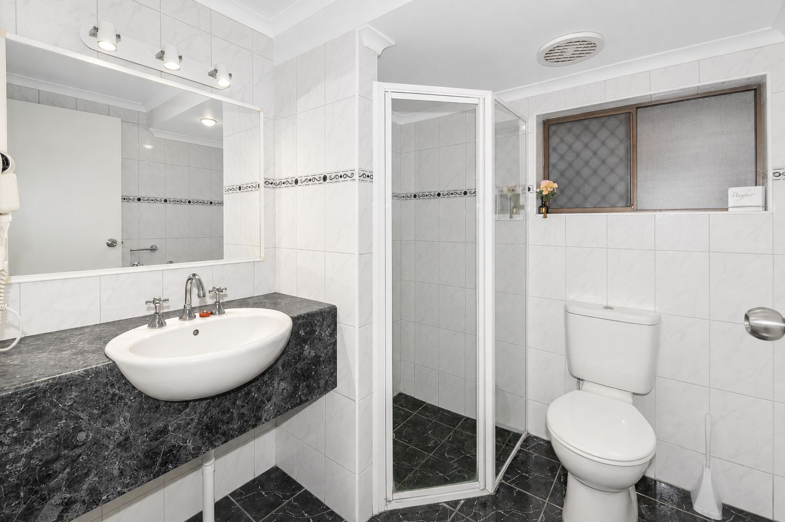 A bathroom with a white sink, a toilet, and a shower area.