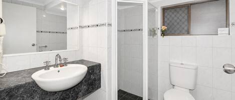 Un baño con lavamanos blanco, inodoro y zona de ducha.