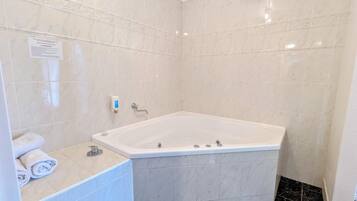 A bathroom with a bathtub, white marble tiles, a hand soap dispenser, and a small towel rack.