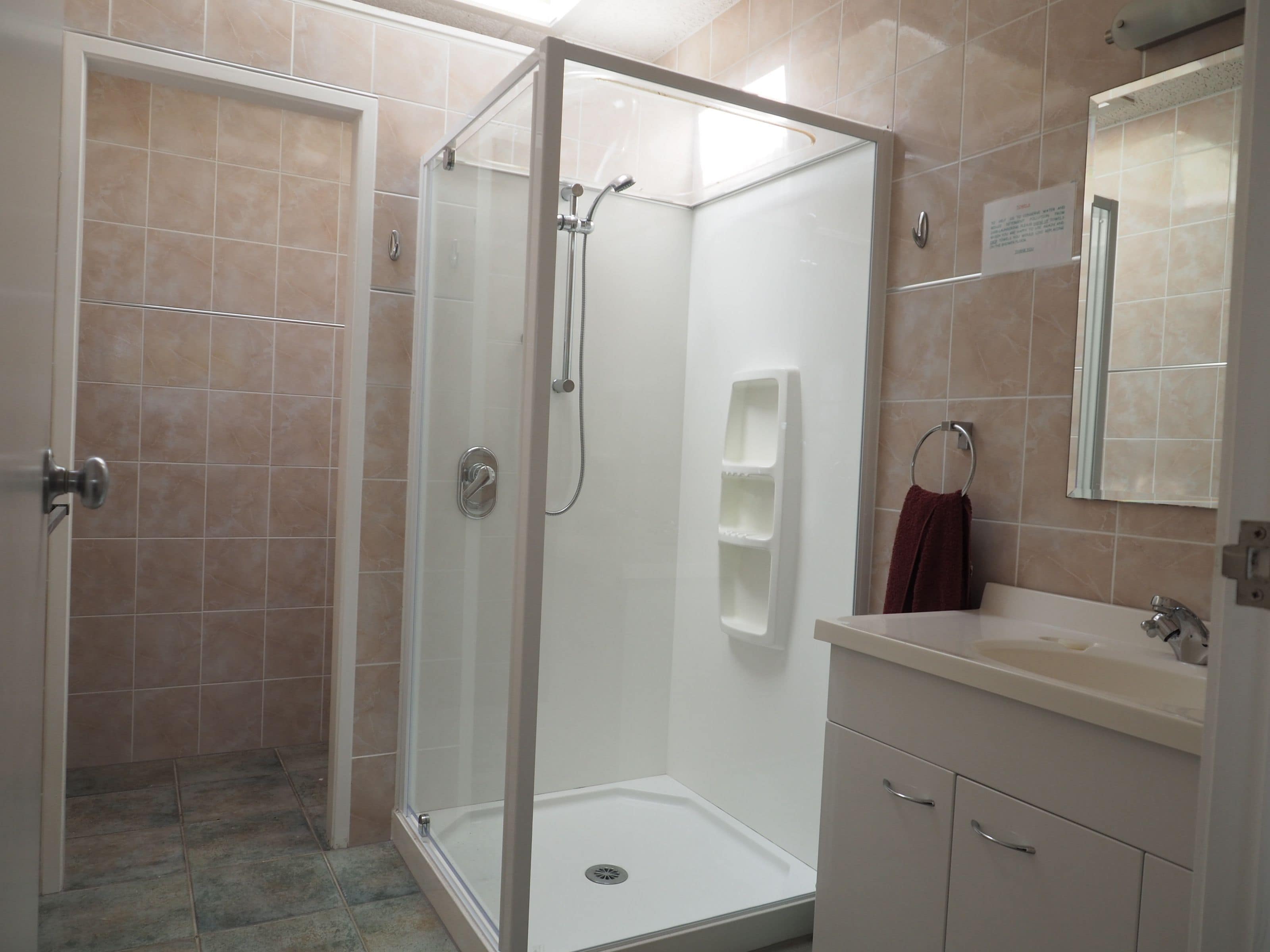 A modern bathroom with a glass-enclosed shower, a vanity with a sink, and a mirror.