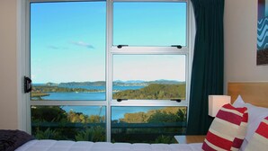 Habitación de hotel con un ventanal que ofrece vistas a un lago y colinas.