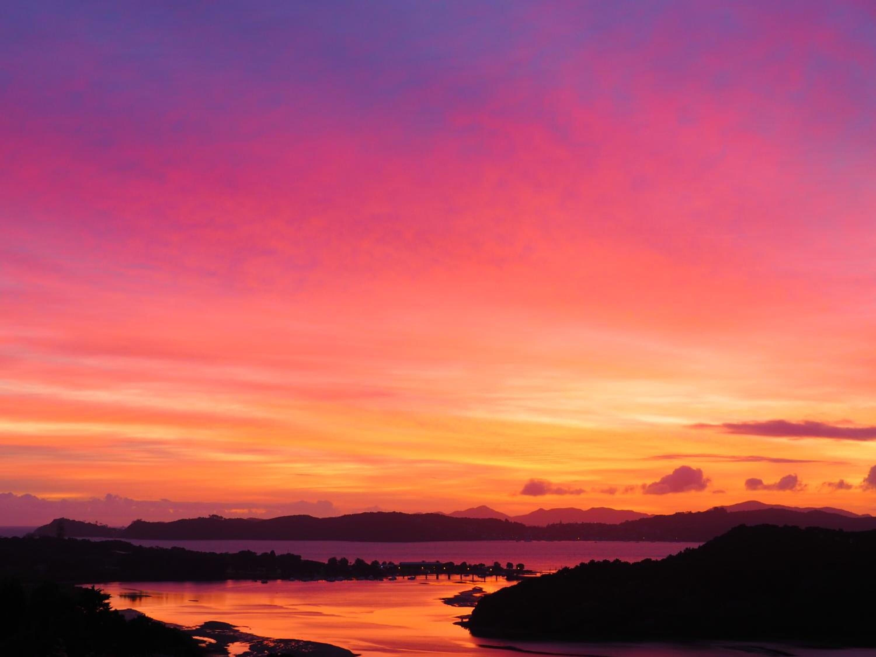 A sunset view over a lake with distant mountains.
