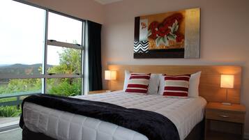 Een hotelkamer met een groot bed, twee bedlampen, een nachtkastje en een schilderij boven het bed.