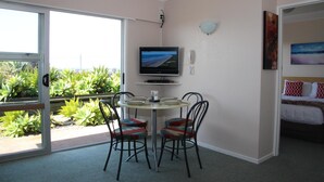 Una habitación con cama, televisor, teléfono y una mesa de comedor con sillas.
