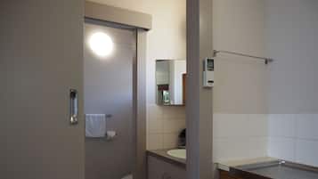 A bathroom with a toilet, sink, mirror, and a towel rack.