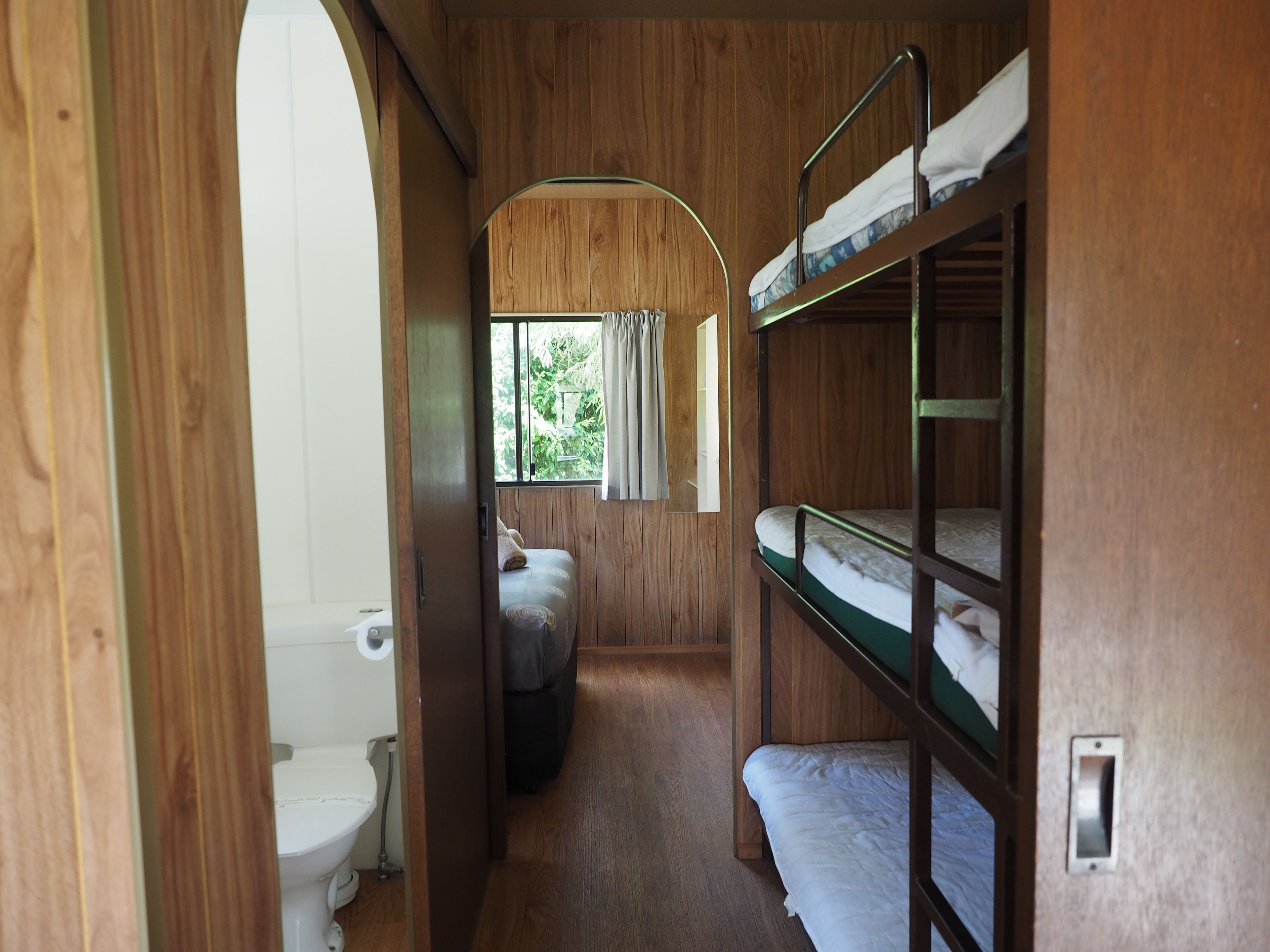 A narrow corridor with bunk beds on one side and a toilet on the other.