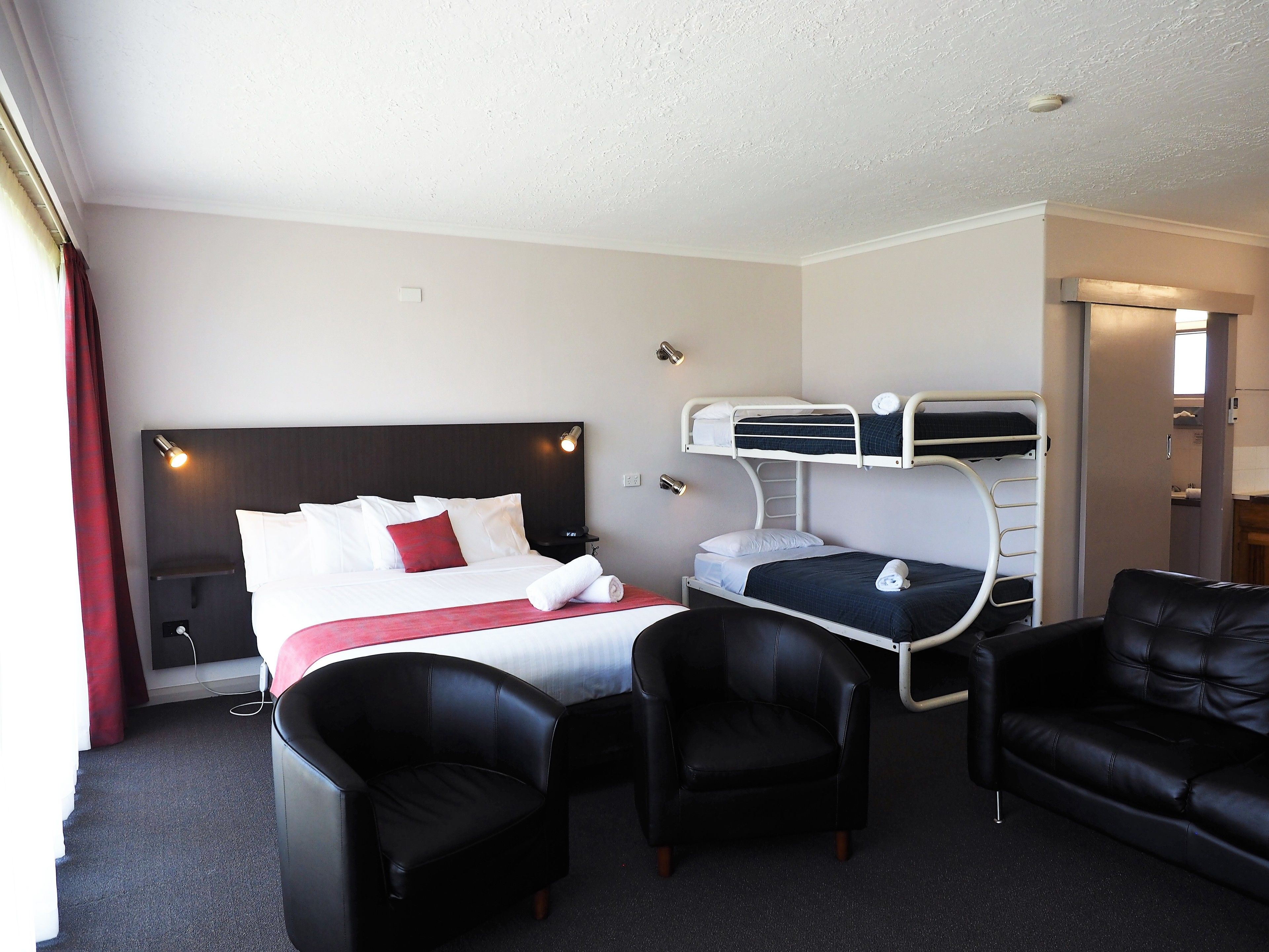 Habitación de hotel con una cama, un escritorio, dos sillas y una cama individual.