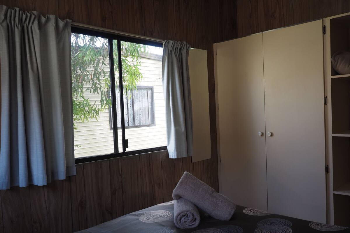 Een kamer met een bed, een kledingkast en een raam met gordijnen.