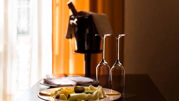 A dining table with a plate of food, two empty wine glasses, and a bottle of wine.