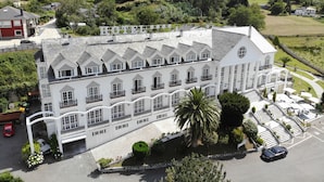 Ein großes, weißes Hotel mit zahlreichen Balkonen und einem zentralen Innenhof mit Palmen.