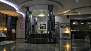 Eine moderne Lobby mit einer zentralen Fontäne, einem Empfangsbereich und einem polierten Boden.