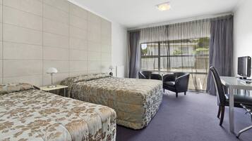 A hotel room with two beds, a desk with a computer, and a chair.