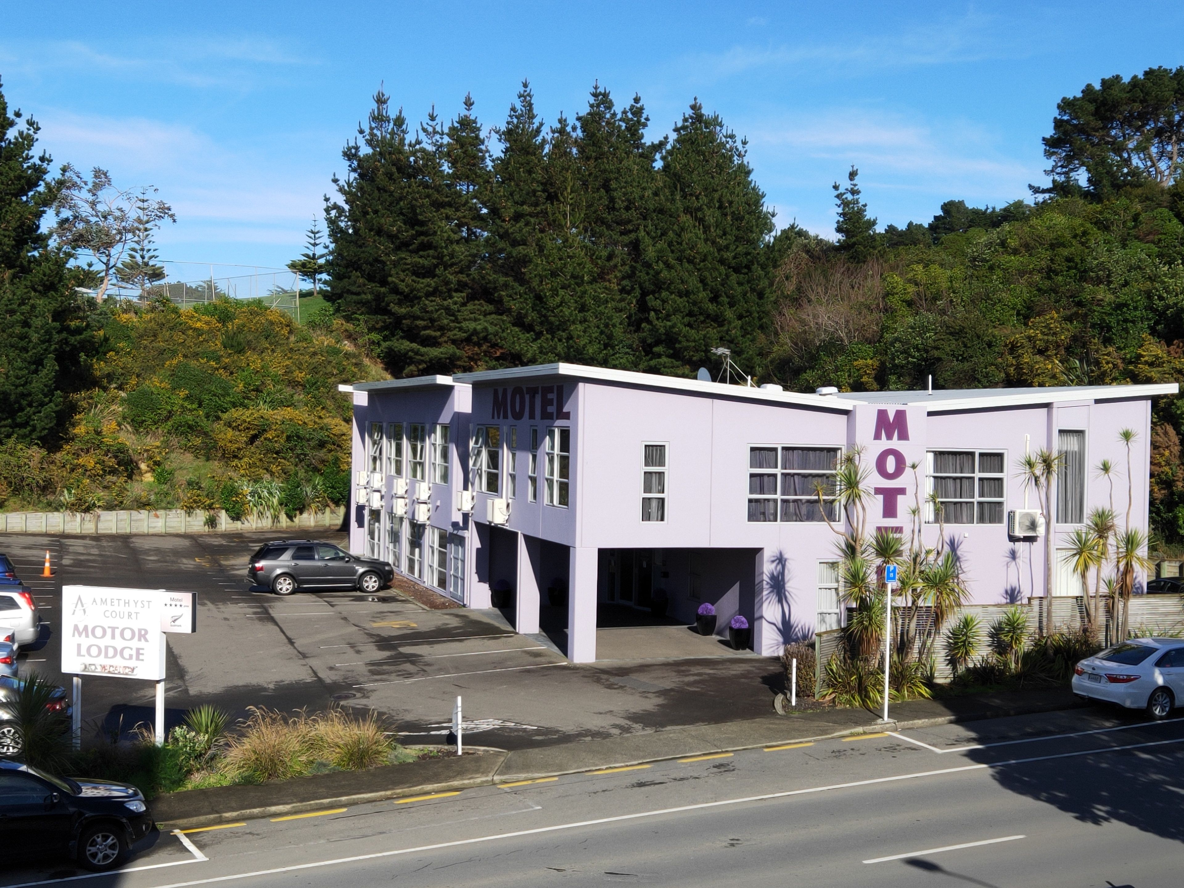A motel with a sign indicating it is the Amethyst Court Motor Lodge.