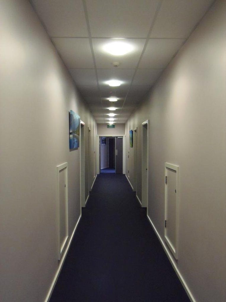 A long, narrow hallway with doors on both sides, leading to individual rooms.