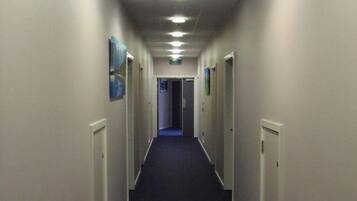 A long, narrow hallway with doors on both sides, leading to individual rooms.