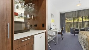 Et lille hotelværelse med tekøkken, skrivebord og seng.