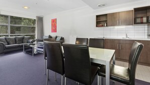 En moderne stue med spisebord og stole, en sofa og et stort vindue.