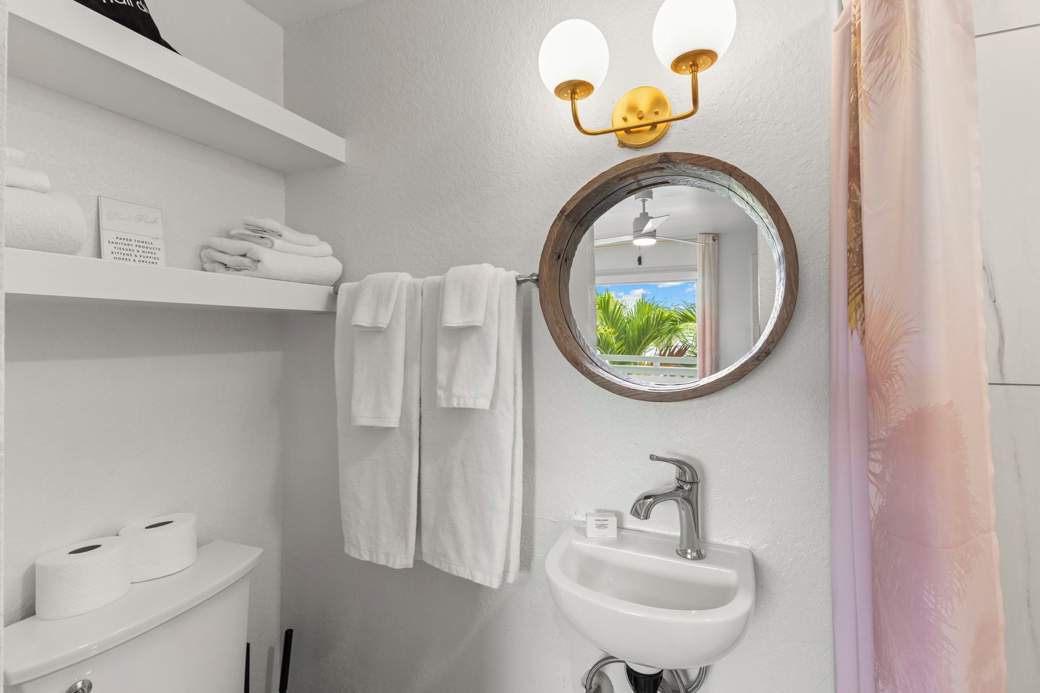 Ein Badezimmer mit einem weißen Waschbecken, einem Spiegel und einem Ablagebereich mit Handtüchern.