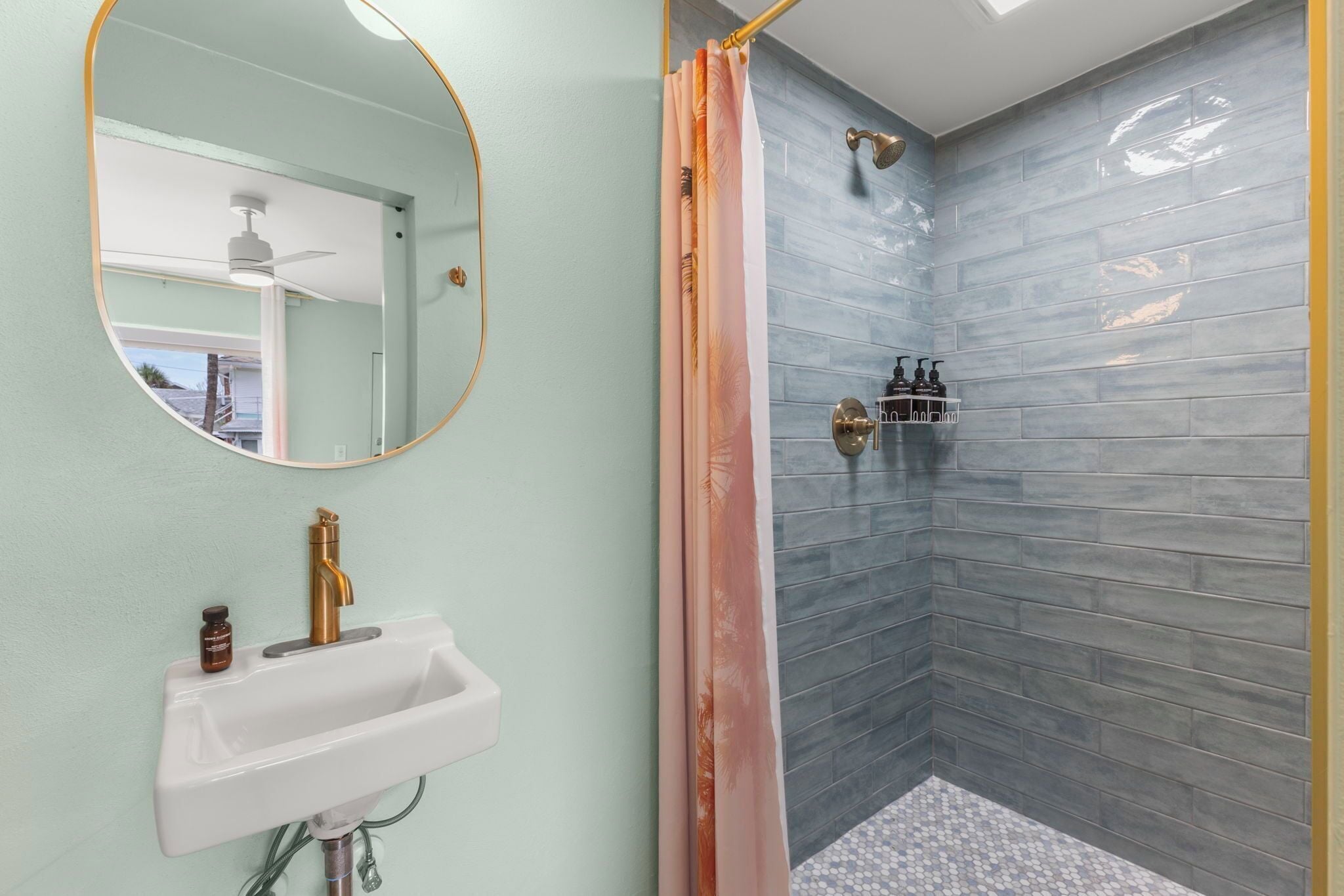 Ein Badezimmer mit Waschbecken, Spiegel, Dusche und Pflegeprodukten.