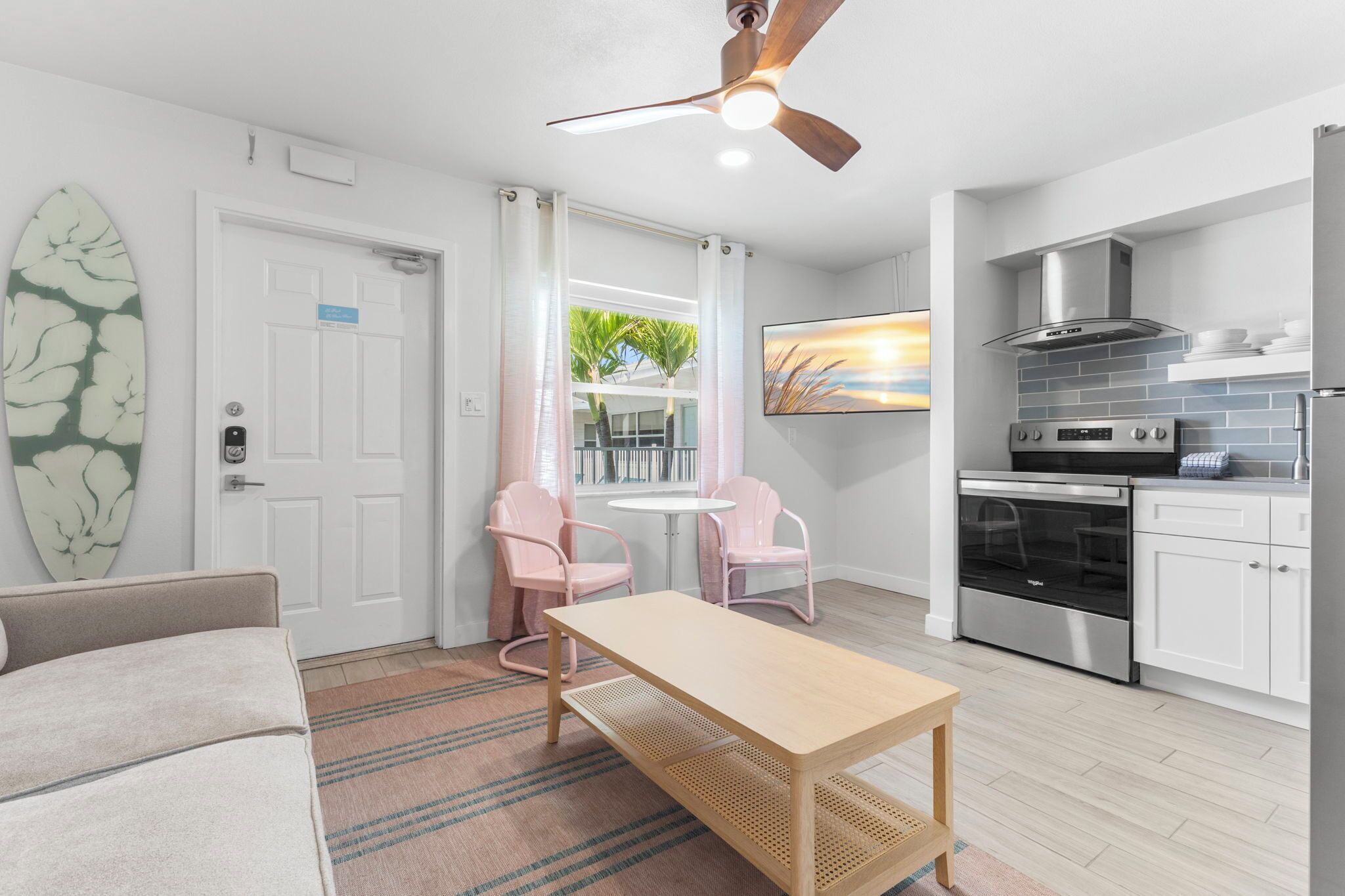 A modern kitchen with stainless steel appliances, a ceiling fan, and a dining area with a table and chairs.