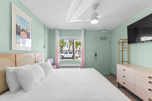 Un dormitorio con cama, cómoda, ventilador de techo, puerta y ventana.