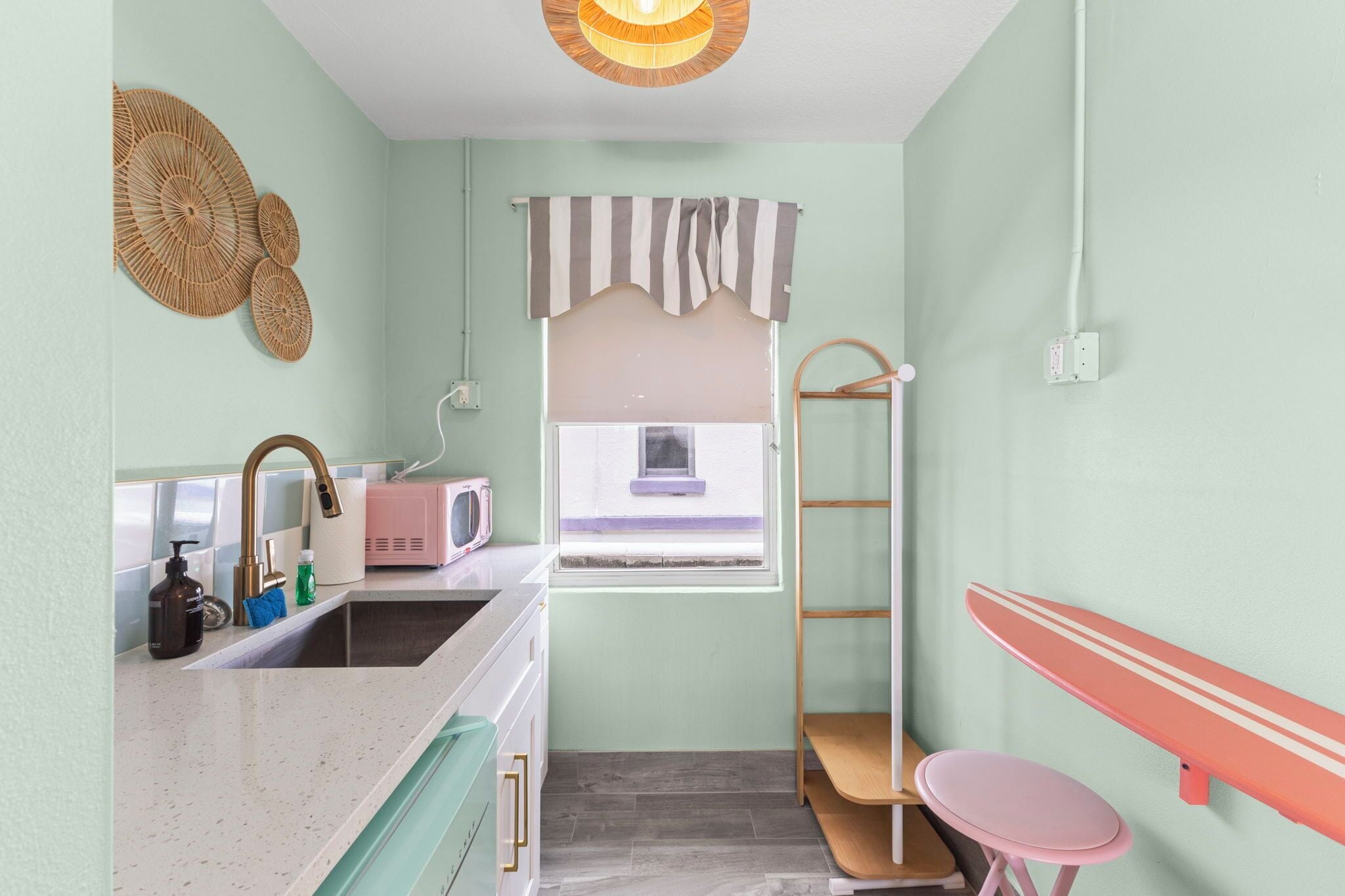 A compact kitchen with a sink, a microwave, and a window.