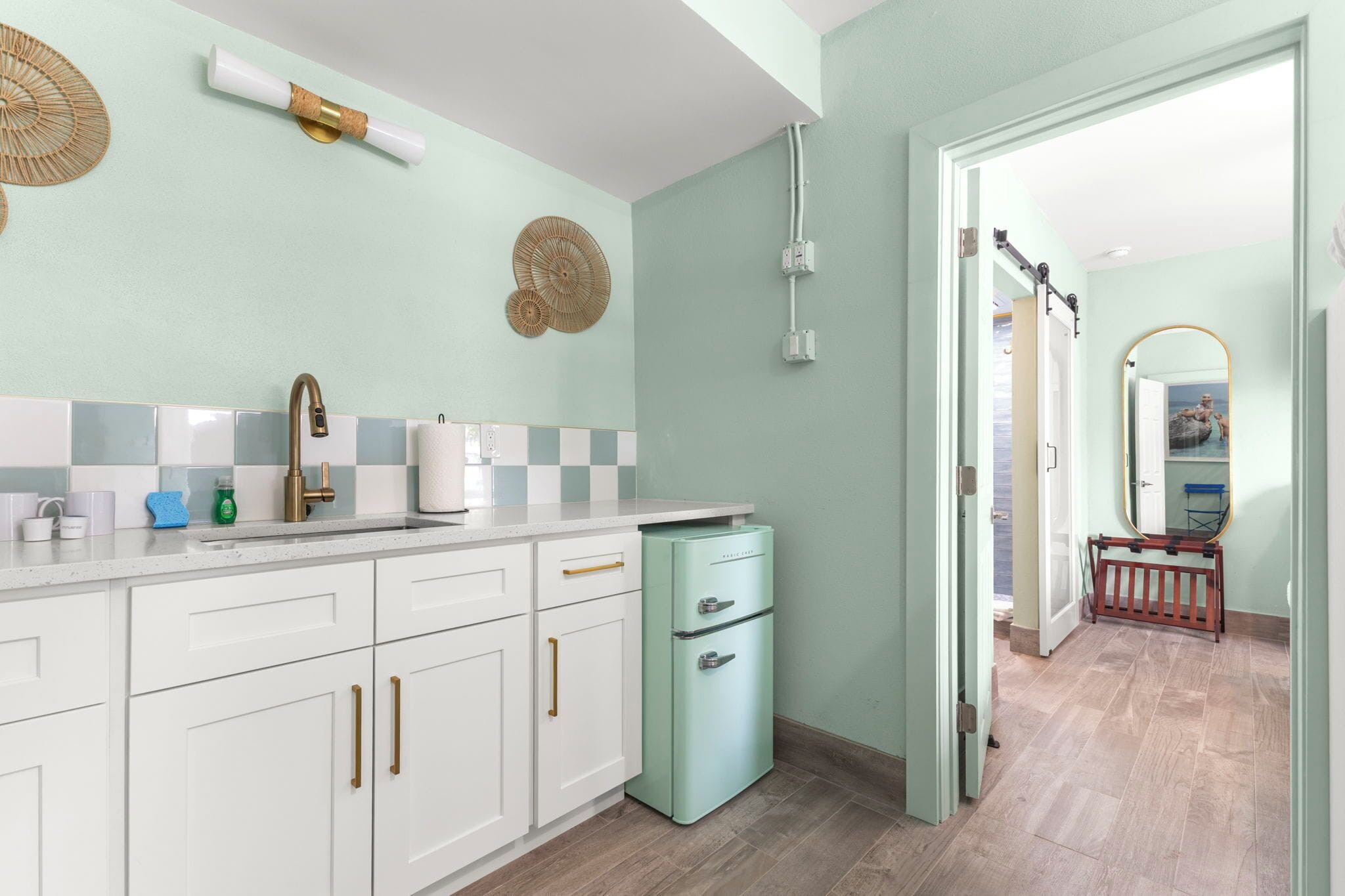 Een keuken met witte kasten, een lichtblauwe koelkast en een betegelde spatwand.