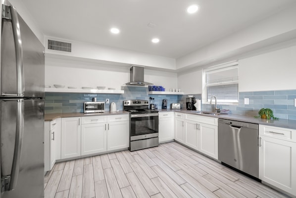 A modern kitchen with white cabinets, stainless steel appliances, and a blue-tiled backsplash.