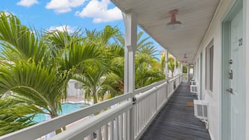 Un balcon extérieur abrité, doté d’une piscine et entouré de palmiers.