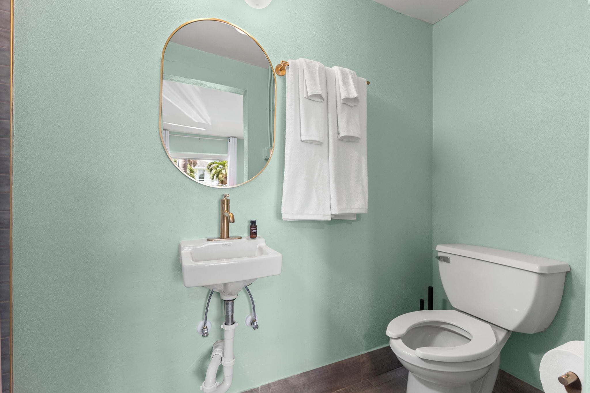 A bathroom with a toilet, sink, and mirror.