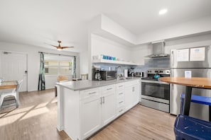 A modern kitchen with white cabinets, stainless steel appliances, and a wooden dining table.