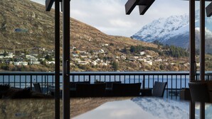 A view from a balcony overlooking a lake with houses and mountains in the background. - Marina Apartments Element Escapes (Queenstown)