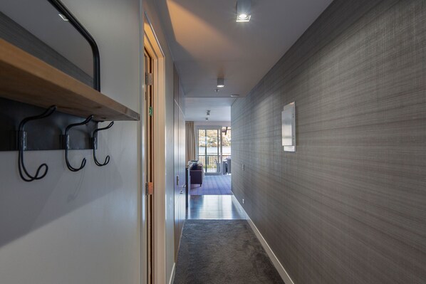 Un couloir avec un banc en bois, un porte-manteau et une vue sur un balcon.
