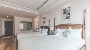Ett hotellrum med två sängar, trägolv, en stor spegel och en inramad tavla på väggen.