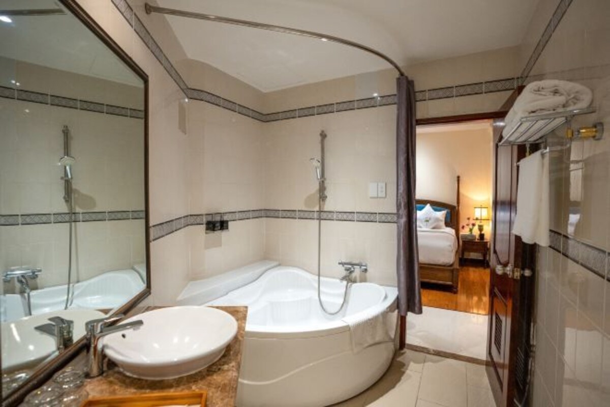 Un baño moderno con una bañera independiente, un espejo grande y un lavamanos separado.