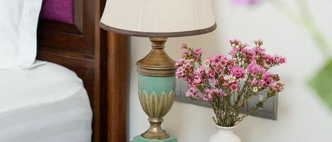 A bedside table with a lamp and a vase of flowers.