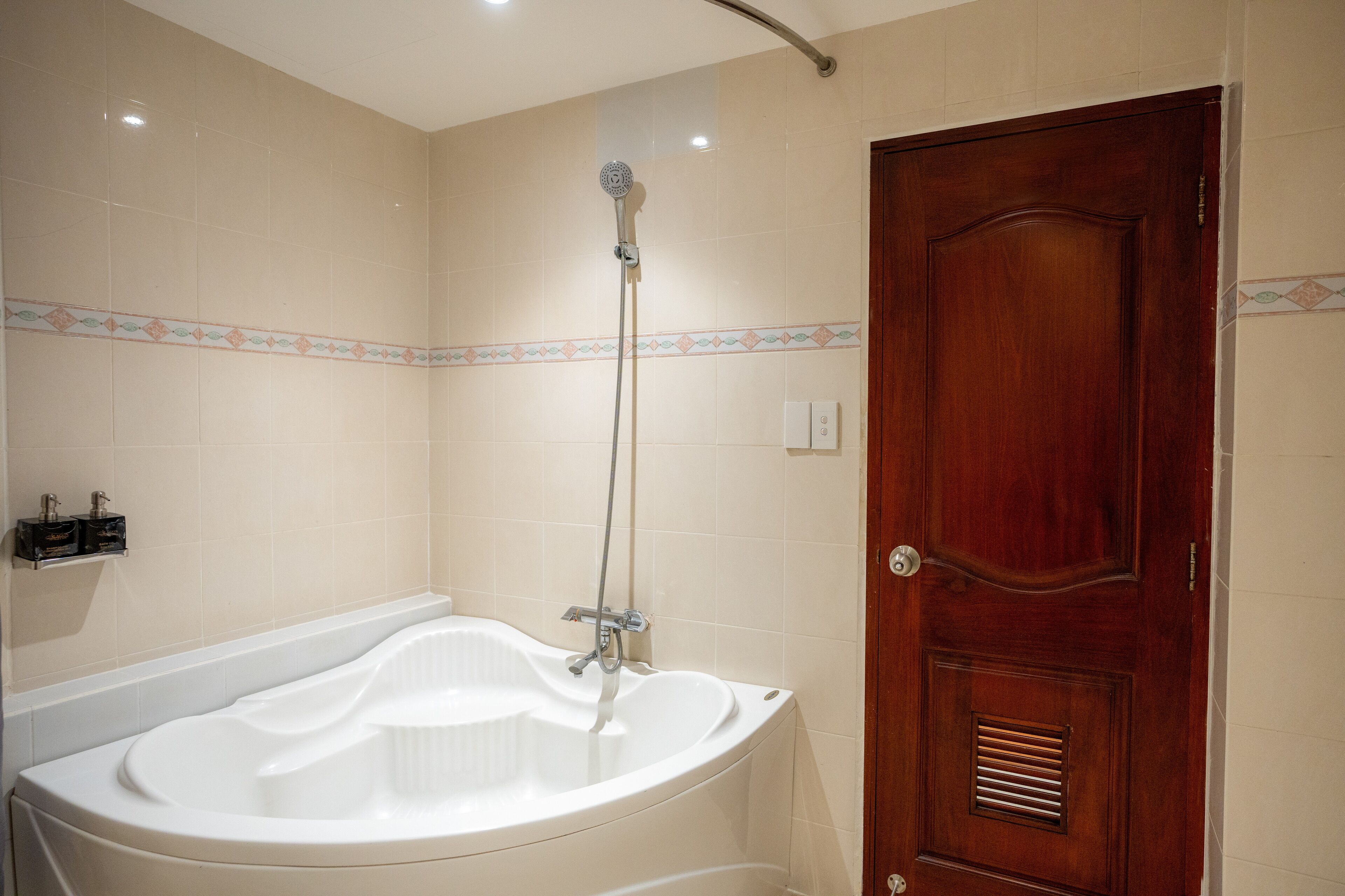 A bathroom with a freestanding bathtub, a showerhead, and a wooden door.