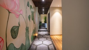 En hall med en v äggmålning som föreställer lotusblommor, ett trägolv och en trappa som leder upp till en övre våning.