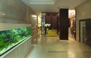 A lobby with a large aquarium, a reception desk, and a decorative wall. - Alagon City Hotel & Spa (Ho Chi Minh City)