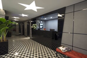 A modern lobby with a checkered floor, a reception desk, and a seating area. - Hotel 81 Premier Hollywood (Singapore)