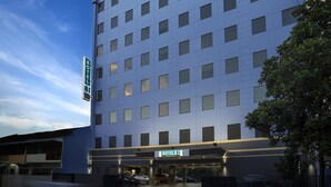 Um hotel com vários andares e fachada moderna, com inúmeras janelas e uma placa indicando Hotel 81.