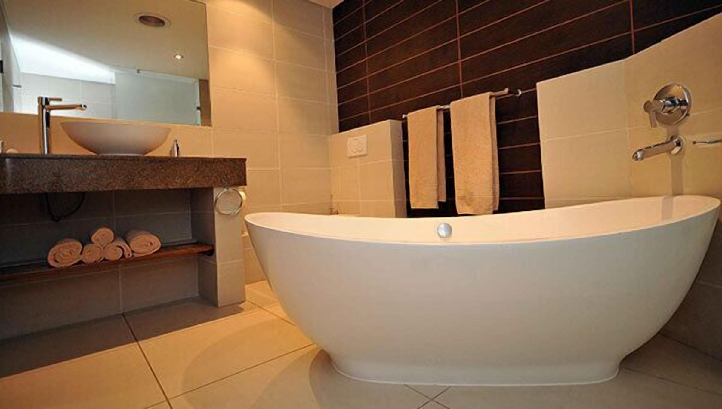 Une salle de bain moderne avec une baignoire sur pieds, un lavabo en forme de vasque et un miroir au-dessus du lavabo.