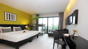 A modern hotel room with a large bed, a desk, a chair, a TV, and a balcony with a view. - Simplitel (Karon)