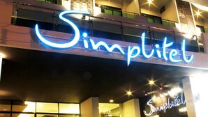 A building with a prominent illuminated sign reading "Simplitel." - Simplitel (Karon)