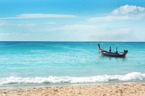 Un bote anclado en una playa arenosa con agua turquesa cristalina.