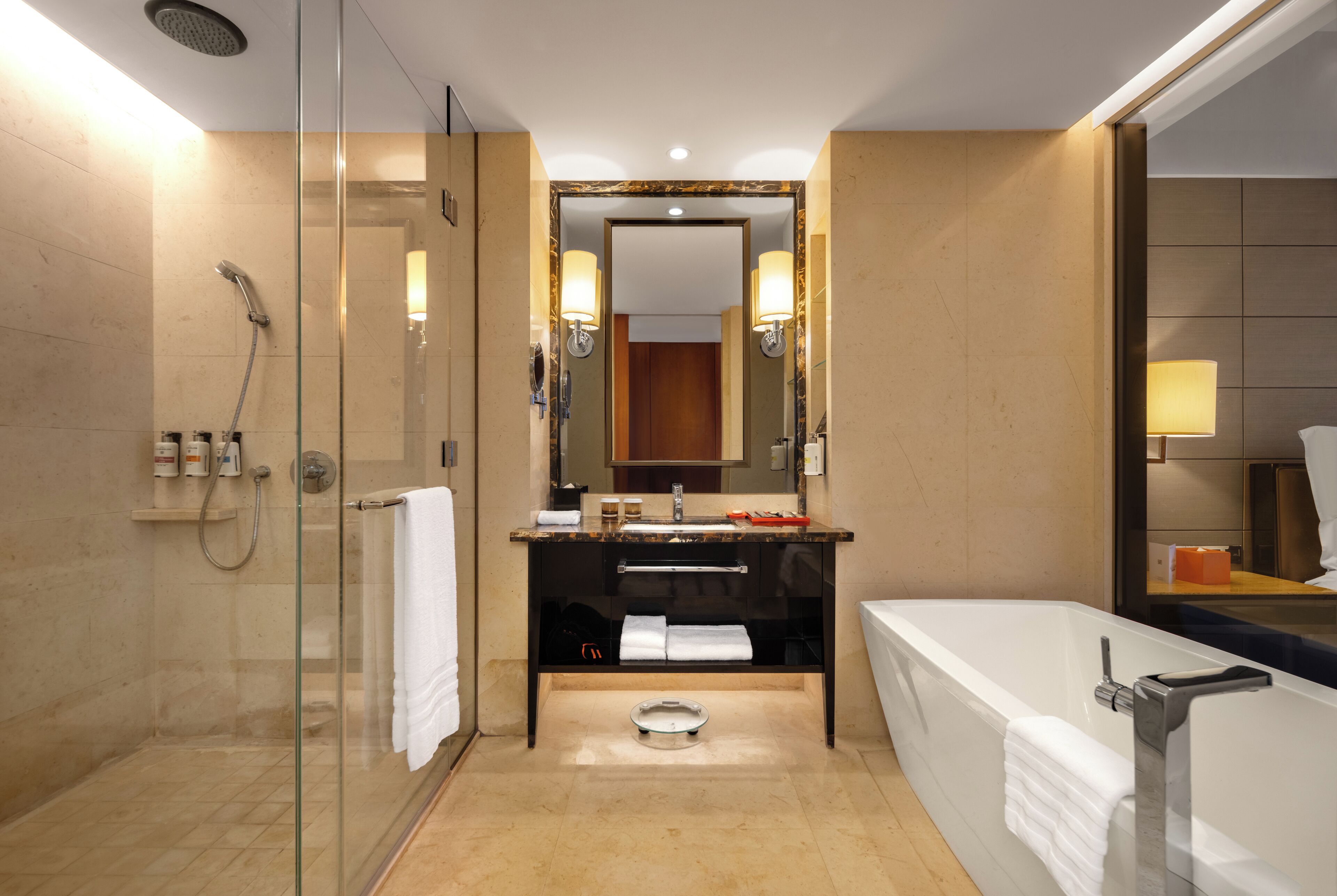 A modern bathroom with a glass-enclosed shower, a large bathtub, and a vanity with a mirror.