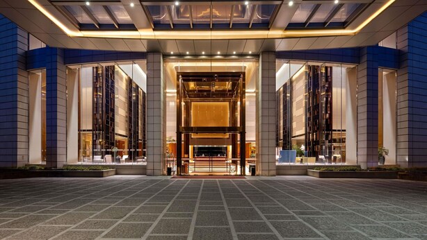 Ein modernes Hotel mit Glasfassade, großzügigem Eingangsbereich und einer zentralen Rezeption.