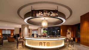 Eine Hotelhalle mit einer zentralen Rezeption vom Typ AT8, einer modernen Kronleuchter und einem großen Fenster.